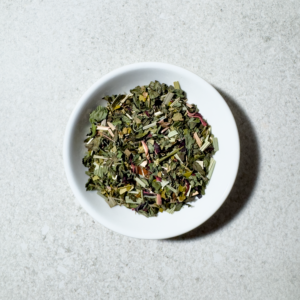 Detailný záber na sypanú organickú zmes Nizu Tea Spring Breeze s lístkami mäty, citrónovou trávou a kvetmi ibišteka na minimalistickom off-white pozadí.